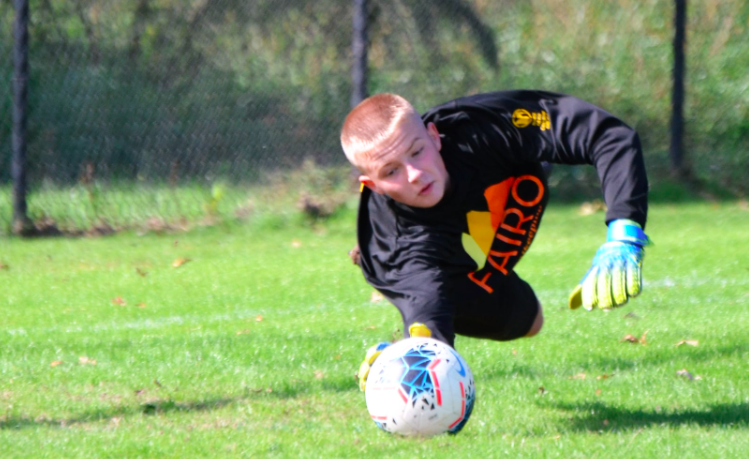 GOALKEEPER is diving for the ball with a fairo Shirt on